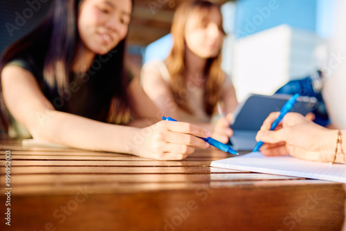 Quadro su tela Young students working together at a table, discussing and writing notes for a g