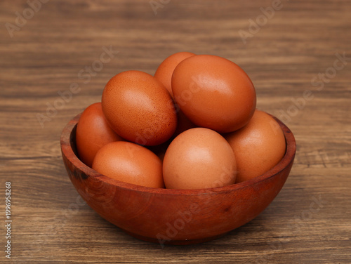 chicken eggs in wooden bowl isolated on wooden background	