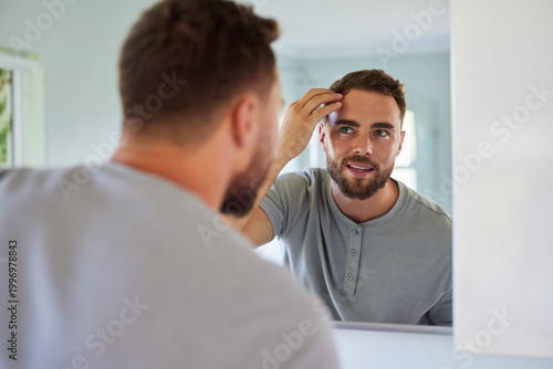 Принти на полотні Man adjusting and checking hair in bathroom mirror