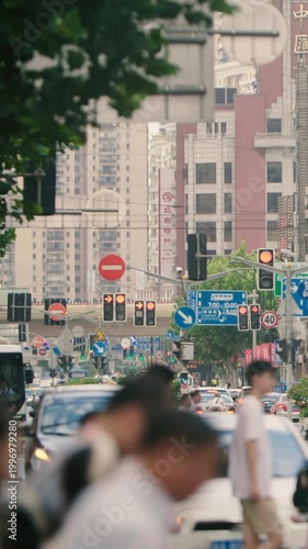 Busy streets of Beijing shift between red and green signals as people walk and vehicles move in the urban landscape during daytime