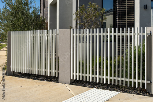 Fotografie A modern white aluminium picket fence with rendered concrete posts fronts a contemporary new home in Australia