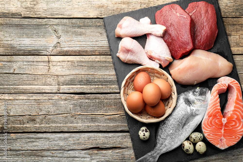Fototapeta premium Different types of fresh raw meat, fish and eggs on wooden table, top view. Space for text