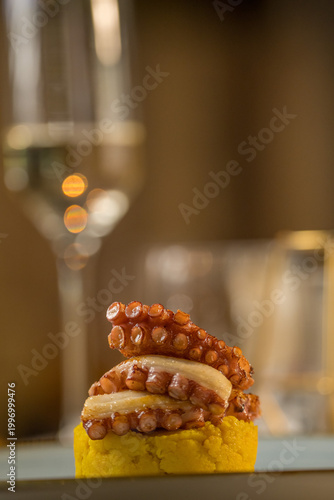 Elegant gourmet appetizer of grilled octopus tentacles served in a fine dining restaurant. The image captures the perfectly charred and caramelized texture of the octopus, beautifully plated with colo