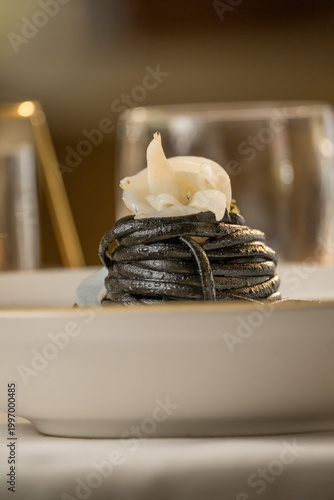 Gourmet presentation of Italian spaghetti with squid ink served on a restaurant table. 