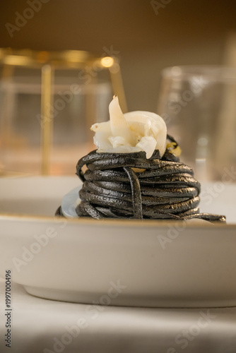 Gourmet presentation of Italian spaghetti with squid ink served on a restaurant table. 