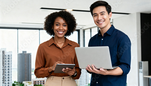 Young happy professional work team of two diverse confident female and male partners employees business people man and woman standing together in office looking at camera, corporate portrait