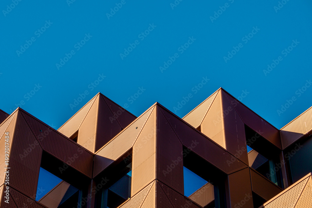 Obraz premium Geometric Form Architecture Shape Building Minimalist Abstract Urban Lines Exterior Featuring Sharp Angular Rooftops Symmetrical Patterns And Rhythmic Projections Under Clear Blue Sky