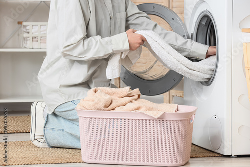 Woman taking towel from washing machine in laundry room