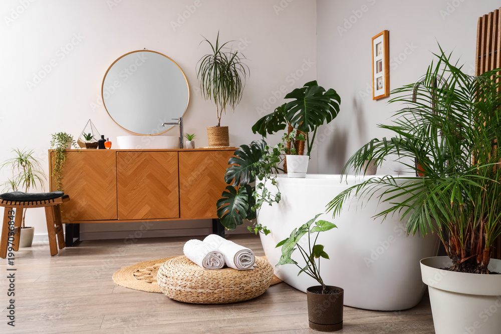 Fototapeta premium Interior of bathroom with green plants, sink and bathtub