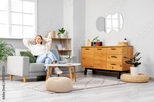 Young woman sitting on grey...