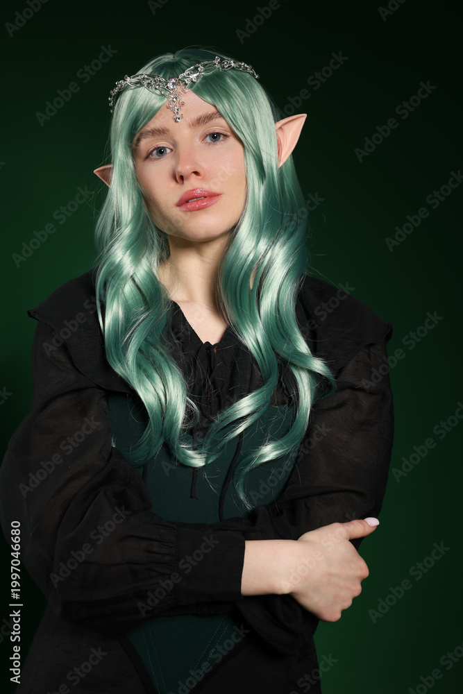 Fototapeta premium Beautiful girl dressed as elf on dark green background