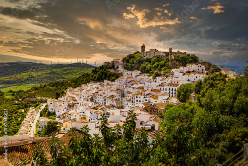 Pueblo blanco andaluz de Casares bajo un cielo dramático al atardecer paisaje de arquitectura tradicional mediterránea con casas encaladas y atmósfera de retiro místico nostalgia y paz absoluta