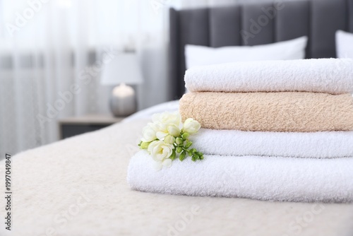 Fotografija Fresh towels and beautiful freesia flowers on bed indoors, closeup