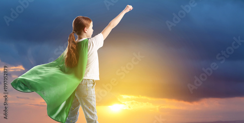 Little superhero. Girl with green cape against sunset sky
