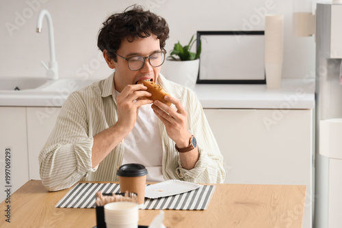 Young man eating tasty hot ...