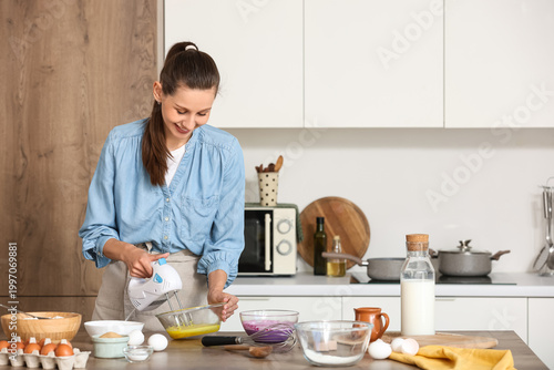 Young woman whipping eggs w...