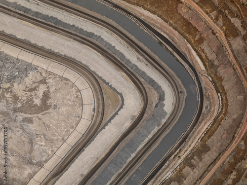 Aerial view of curving terraces and a winding dark channel, revealing contrasting earthy tones, Tucson, Arizona, United States.