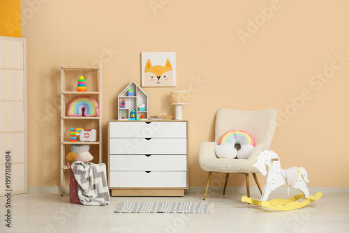 Foto Interior of children's room with armchair, many toys in shelving unit, rocking h