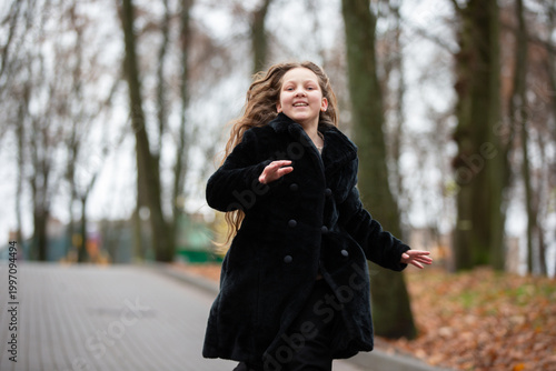 фотографія Girl runs along a path in a park during a cloudy day with trees in the backgroun