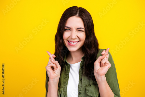 Photos Young woman crossing her fingers and winking with a hopeful smile against a brig