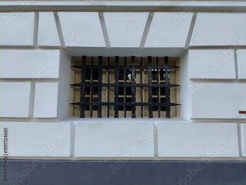 old windows with black security bars on white wall