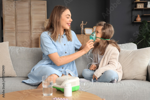 Fotografía Sick little girl with her mother using nebulizer at home