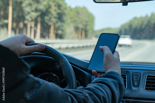 Photography A Distracted Driver Grips the Steering Wheel While Using a Smartphone on a Sceni