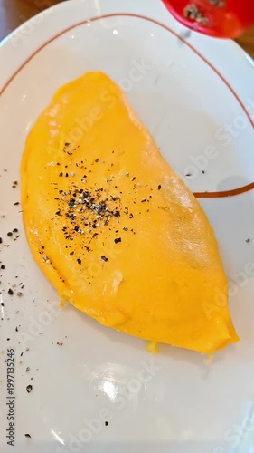 Pouring grounded black pepper onto omelet, French Food cuisine, Seasoning Spice, Tasty Fluffy Egg Dish