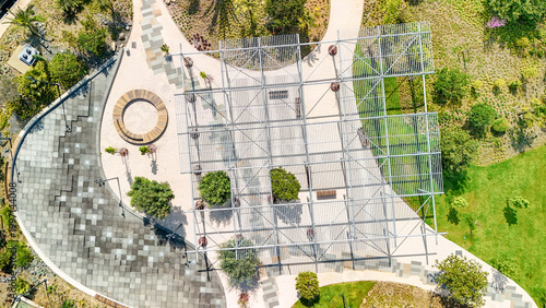 Картината върху платно Urban park with abstract metal pergola casting geometric shadows over pathways,