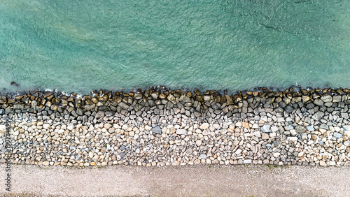 Photography Clear turquoise water washing over a rocky breakwater protecting the shore, crea