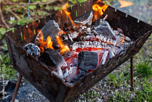 Hot burning charcoal and bright orange flames in metal grill brazier for outdoor barbecue.