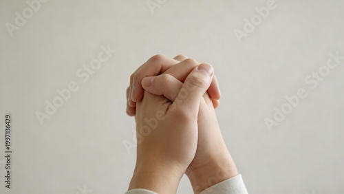 Hands clasped together in front of a plain wall
