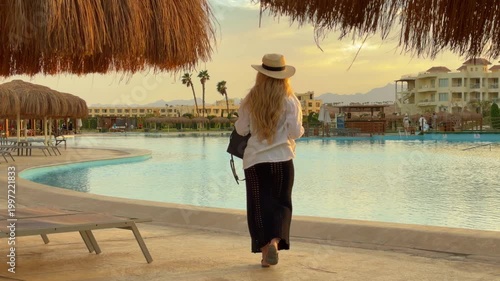 Relaxed Female Traveler Appreciating Peaceful Evening Ambiance Beside Pool And Palms