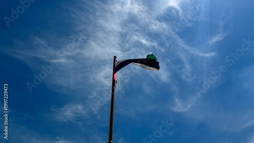 Bild auf Leinwand Low angle view of the United Arab Emirates flag waving on a flagpole against a c