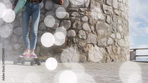 Woman entering left carrying mint board skating past tower with bokeh accenting motion heading surf