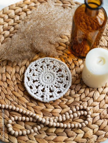 Boho Decor Flatlay with Macrame Coaster, Pampas Grass, Amber Glass Bottle, Ceramic Beads and Neutral Candle on Woven Rattan in Soft Natural Light