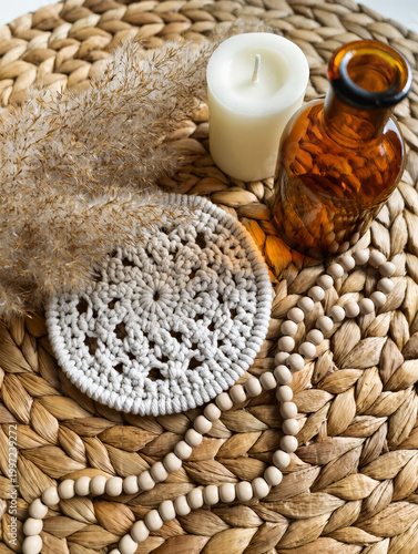 Boho Decor Flatlay with Macrame Coaster, Pampas Grass, Amber Glass Bottle, Ceramic Beads and Neutral Candle on Woven Rattan in Soft Natural Light