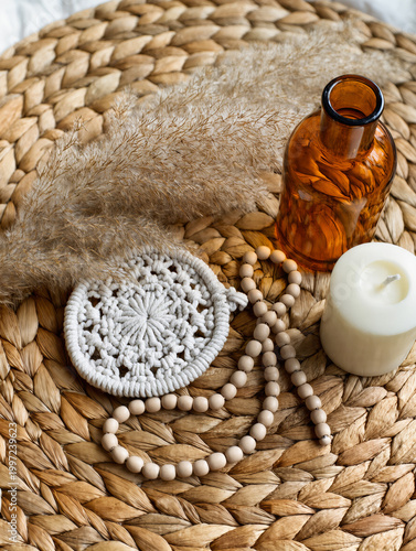 Boho Decor Flatlay with Macrame Coaster, Pampas Grass, Amber Glass Bottle, Ceramic Beads and Neutral Candle on Woven Rattan in Soft Natural Light