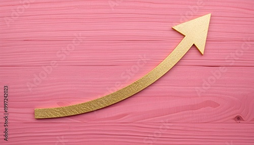 A gold glitter arrow pointing upwards on a pink wooden background, symbolizing growth and success.