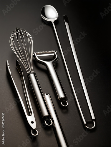 Chrome Kitchen Tools Flatlay with Whisks, Peelers and Tongs on Black Matte Surface Highlighting Reflective Metal Shine and Clean Minimal Composition