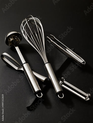 Chrome Kitchen Tools Flatlay with Whisks, Peelers and Tongs on Black Matte Surface Highlighting Reflective Metal Shine and Clean Minimal Composition