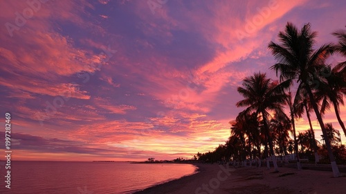 Vibrant sunset over ocean with silhouettes of palm trees and colorful sky