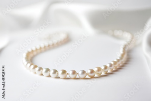 Elegant Pearl Necklace Resting on White Fabric With Soft Light Shining Through