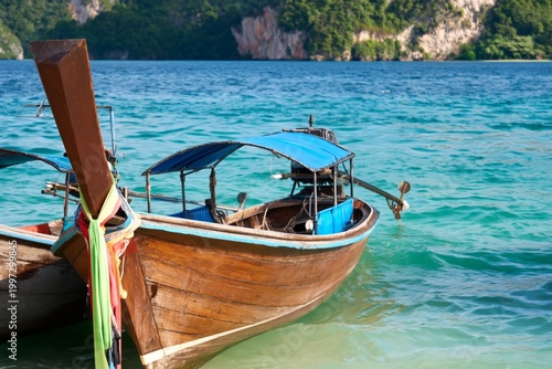 Wooden Boat Anchored in Blue Water Near Rocky Mountains on a Sunny Day