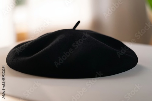 Black Beret Sits on a Marble Table Near a Green Plant With Sunlight Shining T...