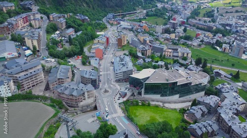 aerial view showcases the picturesque town of La Massana in Andorra, nestled within the lush green Pyrenean mountains during the summer. The footage captures the blend of urban development and natural