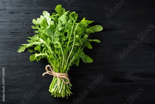 Fresh Arugula Tied With Twine on a Black Wooden Surface in a Kitchen Setting