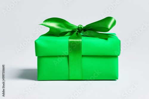 Bright Green Gift Box is Wrapped Neatly With a Satin Bow on a Light Gray Back...