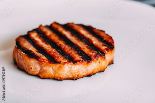 Sliced Grilled Meat Patty Placed on a White Plate at a Kitchen Table During M...
