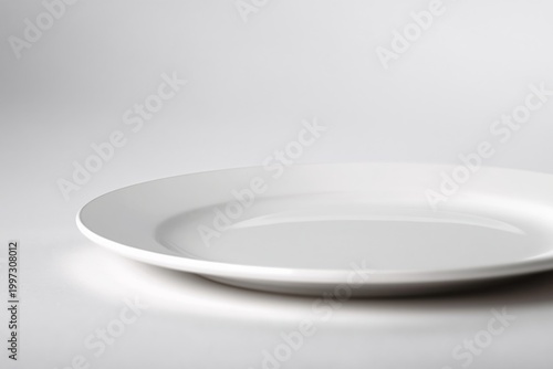 Empty White Plate on a Smooth Surface in a Simple Setting for Dining or Servi...